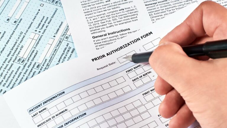 Picture of hand with pen filling out a Prior Authorization form