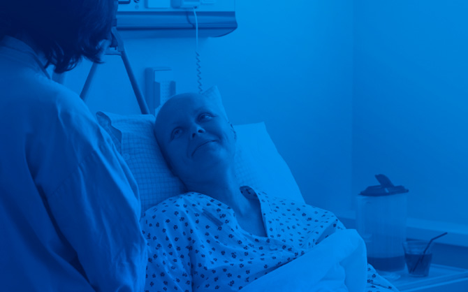 Hospital patient in bed looking up at doctor with Eviti Branded Blue Gradient overlay