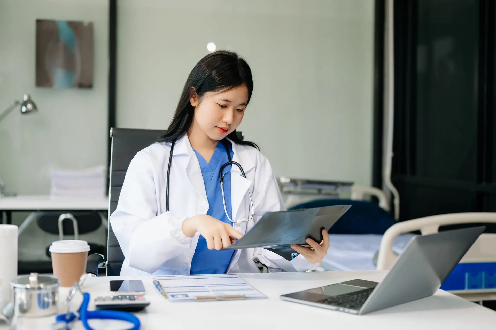 Female doctor examining an X-ray at her desk in a clinic
